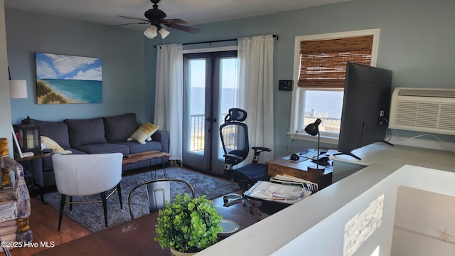living area with plenty of natural light, french doors, a wall unit AC, and ceiling fan
