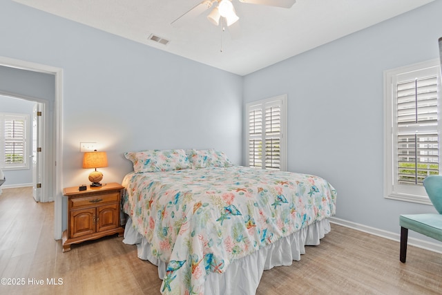 bedroom with light wood-style floors, baseboards, visible vents, and multiple windows