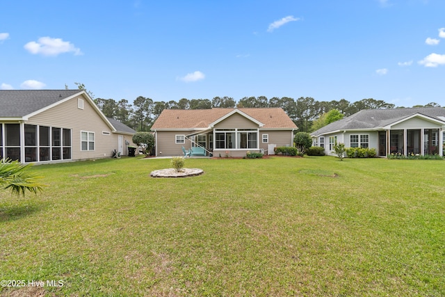 rear view of house featuring a sunroom and a lawn