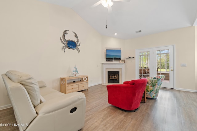 living room featuring wood finished floors, visible vents, vaulted ceiling, and baseboards