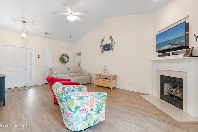living area with a fireplace with flush hearth, a ceiling fan, visible vents, baseboards, and wood finished floors