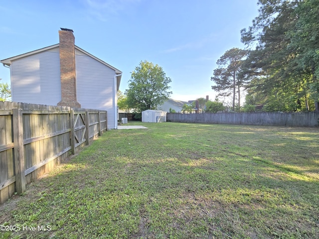 view of yard with a fenced backyard, an outdoor structure, and a storage unit