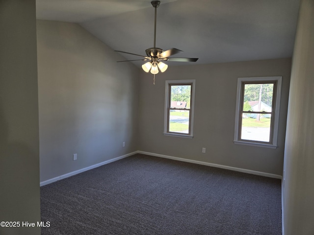 empty room with dark colored carpet, baseboards, ceiling fan, and a healthy amount of sunlight