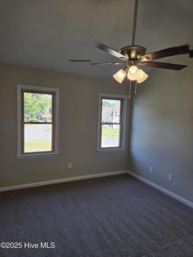 unfurnished room with ceiling fan, baseboards, dark colored carpet, and plenty of natural light