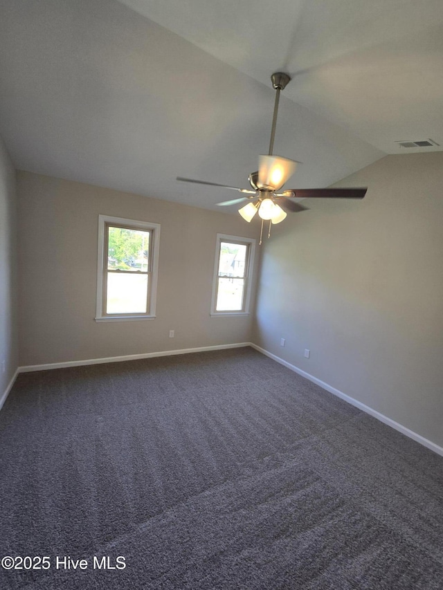 spare room with dark carpet, ceiling fan, baseboards, and visible vents
