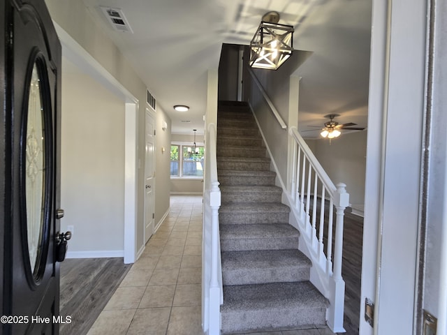 stairs featuring visible vents, tile patterned floors, baseboards, and ceiling fan