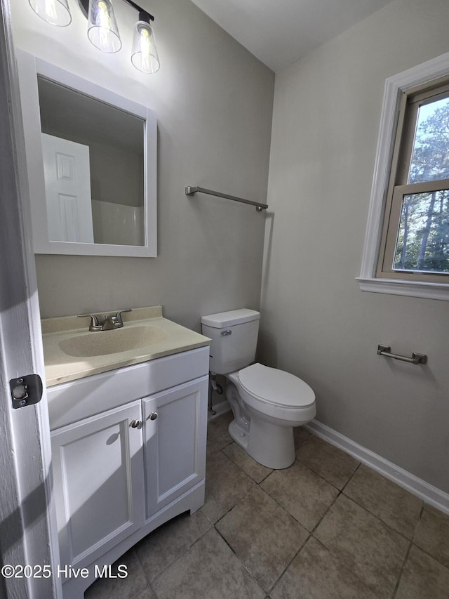 bathroom with baseboards, vanity, tile patterned flooring, and toilet