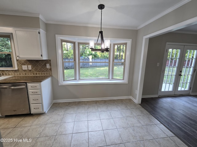 kitchen with white cabinets, dark countertops, stainless steel dishwasher, and a wealth of natural light