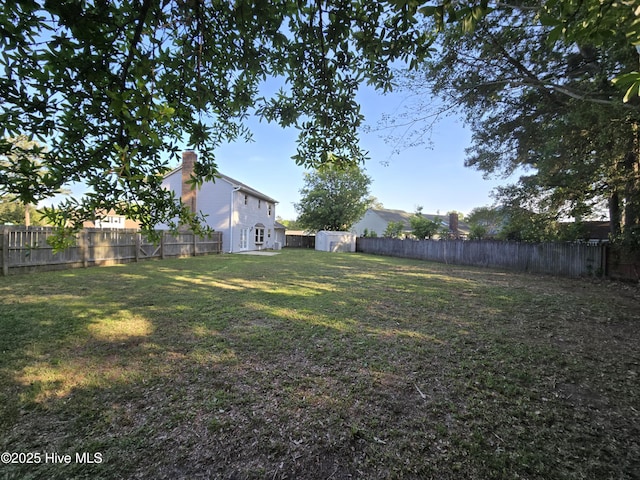 view of yard with a fenced backyard, an outbuilding, and a storage shed