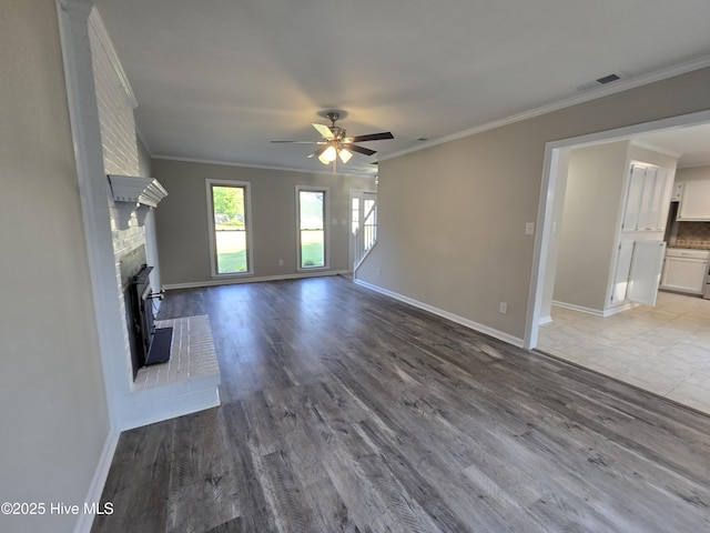 unfurnished living room featuring ceiling fan, baseboards, crown molding, and wood finished floors