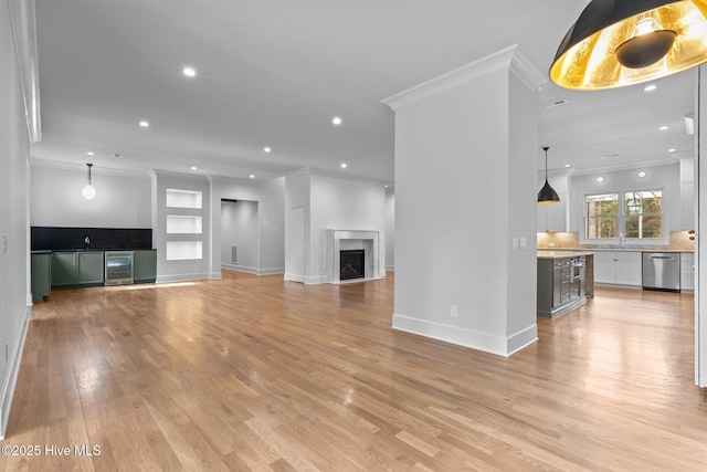 unfurnished living room featuring light wood-style floors, ornamental molding, recessed lighting, and a sink