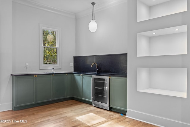 bar featuring hanging light fixtures, wet bar, light wood-type flooring, wine cooler, and ornamental molding