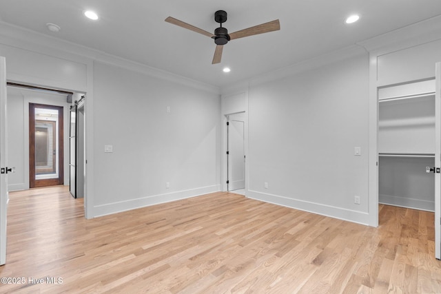 unfurnished bedroom featuring light wood-style flooring, recessed lighting, baseboards, a spacious closet, and ornamental molding