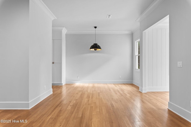 interior space with baseboards, visible vents, ornamental molding, and light wood finished floors