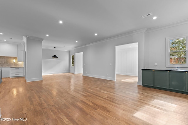 unfurnished living room with visible vents, baseboards, light wood finished floors, ornamental molding, and recessed lighting