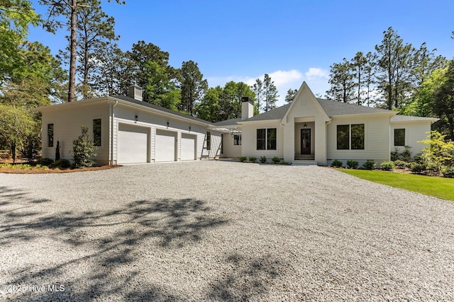 view of front of property with an attached garage, driveway, and a chimney