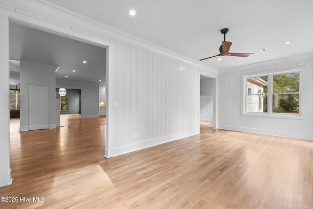 unfurnished living room with crown molding, baseboards, ceiling fan, and light wood-style flooring