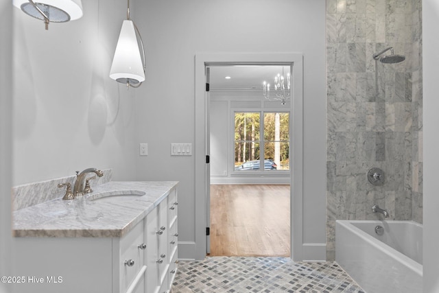 bathroom featuring vanity, baseboards, tile patterned floors, an inviting chandelier, and washtub / shower combination