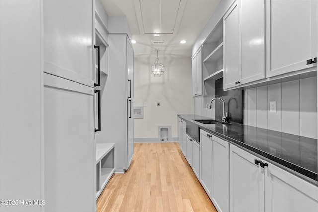 kitchen with open shelves, dark stone countertops, recessed lighting, a sink, and light wood finished floors