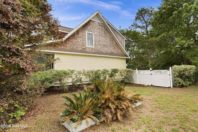 view of property exterior featuring fence, a yard, and a gate
