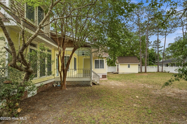 view of yard with an outdoor structure, a ceiling fan, a storage unit, and fence