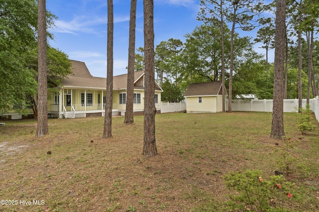 view of yard with an outbuilding, a shed, a fenced backyard, and covered porch