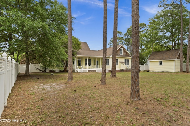 back of house featuring a porch, a fenced backyard, a yard, and an outdoor structure