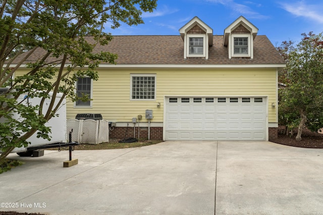 view of front of home featuring concrete driveway, a shingled roof, and a garage