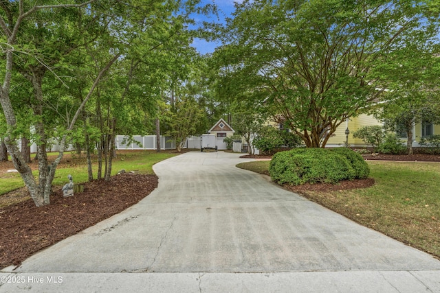 view of home's community with fence, driveway, and a yard