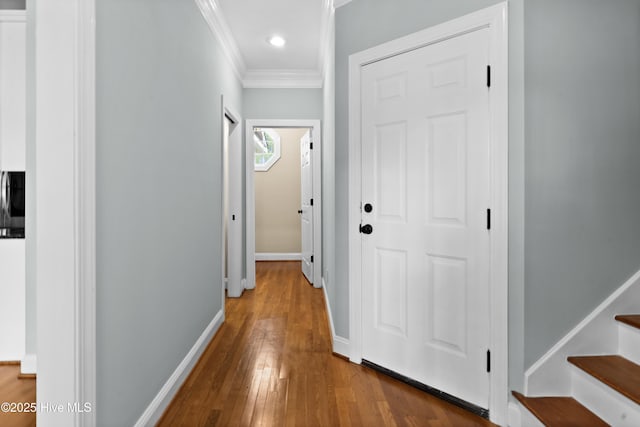 hallway with hardwood / wood-style floors, baseboards, ornamental molding, and stairway