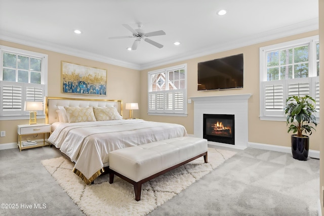 carpeted bedroom featuring baseboards, a fireplace with flush hearth, multiple windows, and crown molding