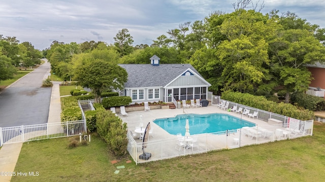 community pool with a lawn, a sunroom, a patio, and fence
