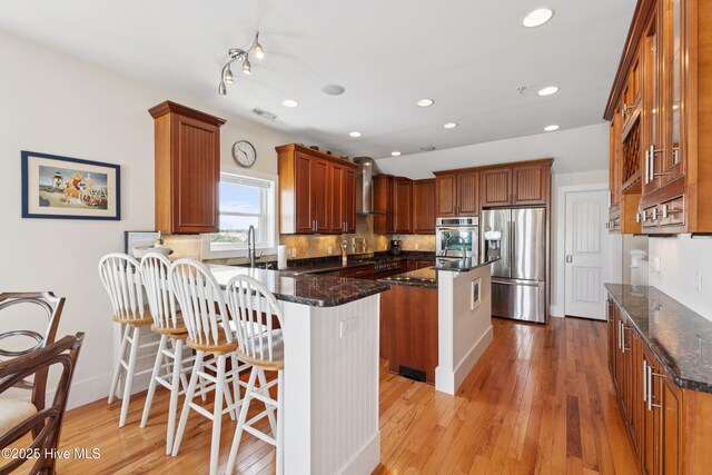 1605 Mackerel Ln Unit 2, Carolina Beach, NC 28428 - kitchen featuring appliances with stainless steel finishes, wall chimney range hood, a peninsula, dark stone counters, and recessed lighting