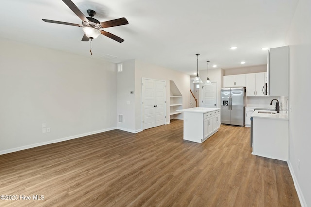 kitchen with ceiling fan, stainless steel appliances, light countertops, a kitchen island, and baseboards