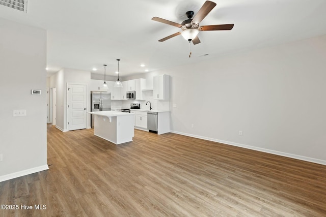 kitchen featuring recessed lighting, stainless steel appliances, visible vents, a kitchen island, and baseboards