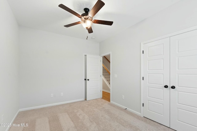 unfurnished bedroom with ceiling fan, a closet, baseboards, and light carpet