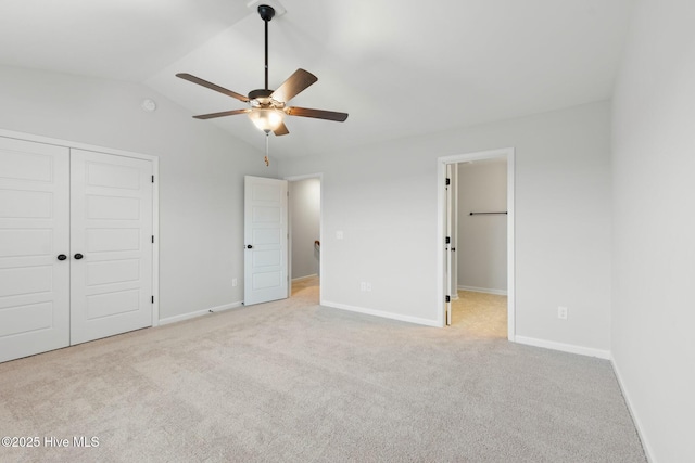 unfurnished bedroom with carpet flooring, baseboards, lofted ceiling, and a closet