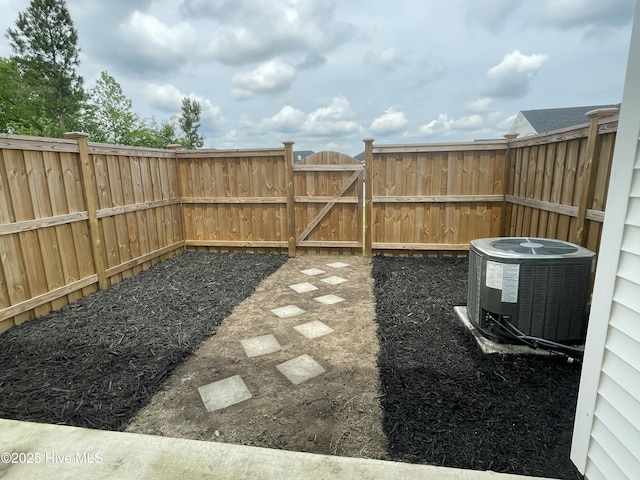view of yard featuring central AC, a fenced backyard, and a gate