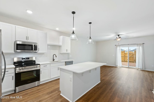 kitchen with decorative backsplash, a sink, appliances with stainless steel finishes, light countertops, and dark wood-style flooring