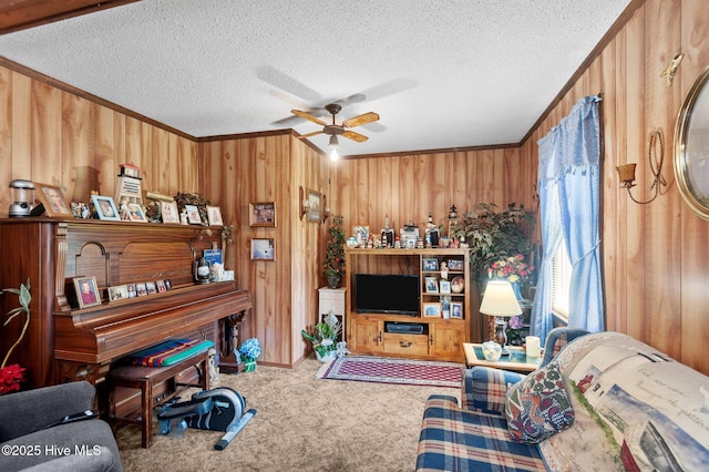 carpeted living room with a ceiling fan, ornamental molding, wooden walls, and a textured ceiling