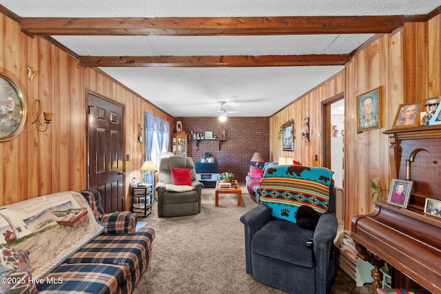 living room featuring carpet, wood walls, a ceiling fan, and beamed ceiling