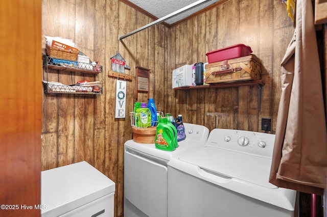 clothes washing area featuring laundry area, wooden walls, a textured ceiling, and independent washer and dryer
