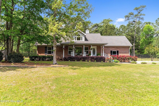 view of front of house featuring a front lawn, fence, a chimney, and brick siding