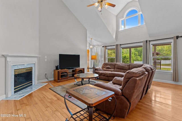 living area with high vaulted ceiling, baseboards, a ceiling fan, and light wood-style flooring