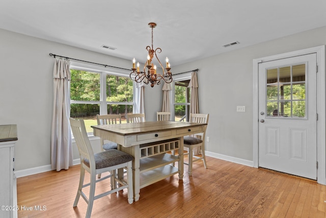 dining room featuring light wood-type flooring, visible vents, and a notable chandelier