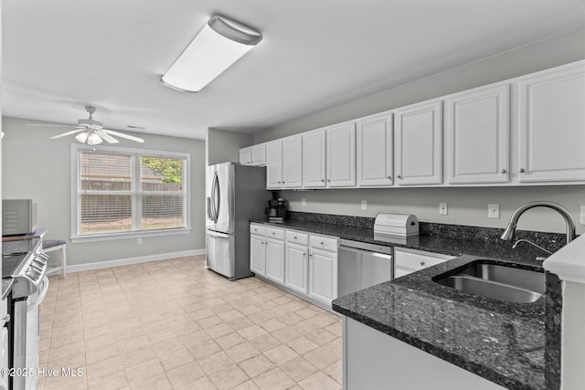 kitchen featuring a sink, dark stone countertops, baseboards, white cabinetry, and appliances with stainless steel finishes