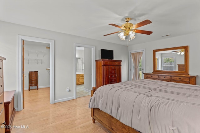 bedroom featuring a closet, a walk in closet, light wood-style flooring, baseboards, and visible vents