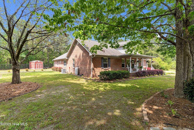 view of side of home featuring a lawn, brick siding, a porch, and a shed