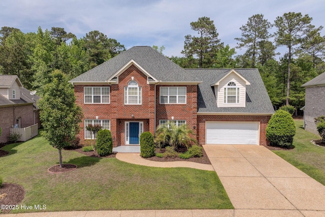 colonial house featuring a shingled roof, a front yard, driveway, and brick siding