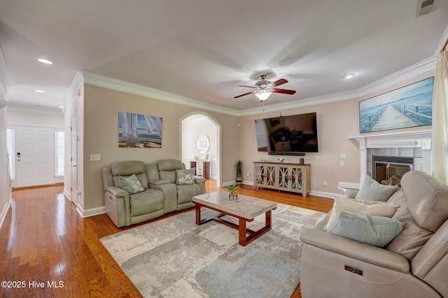 living room featuring baseboards, ornamental molding, and arched walkways